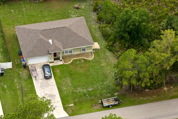 Aerial view of typical contemporary american private house with roof top covered with asphalt shingles and green lawn on yard