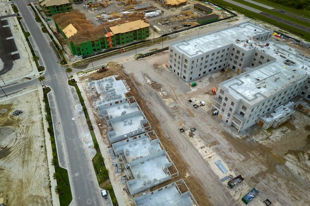 Aerial view of unfinished frames of apartment buildings ready for mounting wooden roof beams under construction Development of residential housing in american suburbs Real estate market in the USA