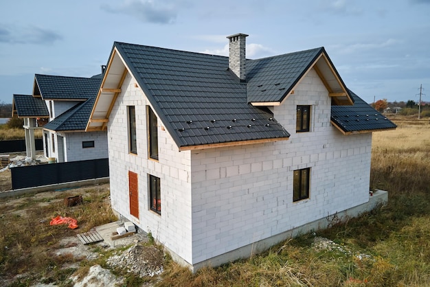 Aerial view of unfinished house with aerated lightweight concrete walls and wooden roof frame covered with metallic tiles under construction