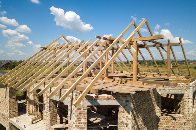 Aerial view of unfinished house with wooden roof frame structure under construction