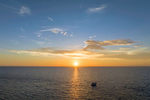 Aerial view of unrecognizable people having fun on white yacht at sunset floating on sea waves with ripple surface Motor boat recreation on ocean surface