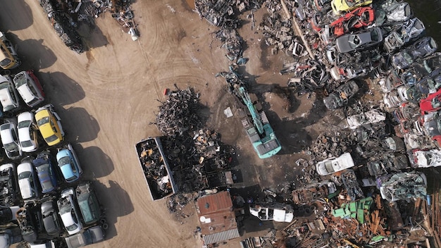 Aerial view video of a car dump where a machine is seen separating old cars into scrap