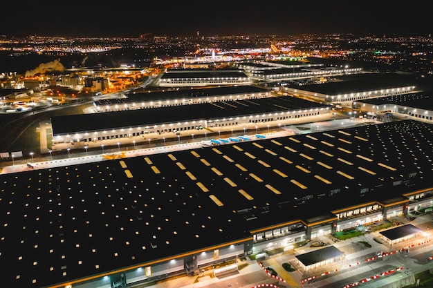 Aerial view of a warehouse of goods at night Aerial view of the logistics center Brightly lit trailers and trucks in a warehouse parking lot