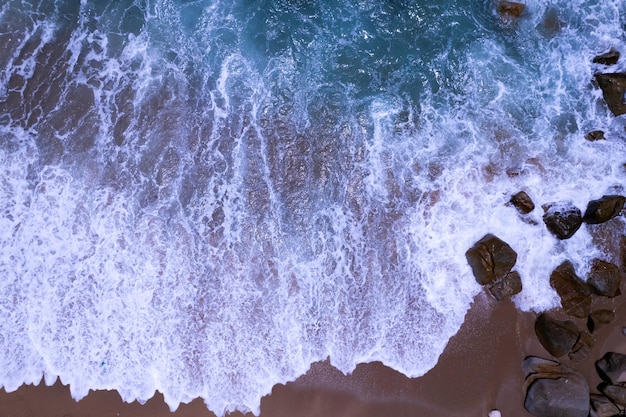 Aerial view waves crashing on sand of beach and soft waves backgroundTop view dark sea sand background