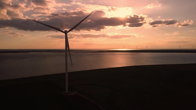 Aerial view of wind turbines and agriculture field near the sea at sunset