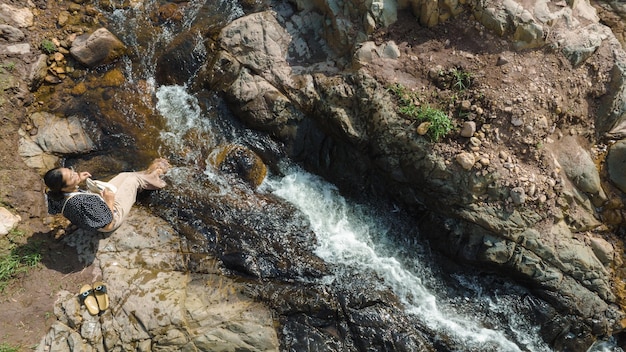 Aerial view of Woman relaxing with beautiful natural water stream the wild forest mountain concept traveling and relaxing on holiday time