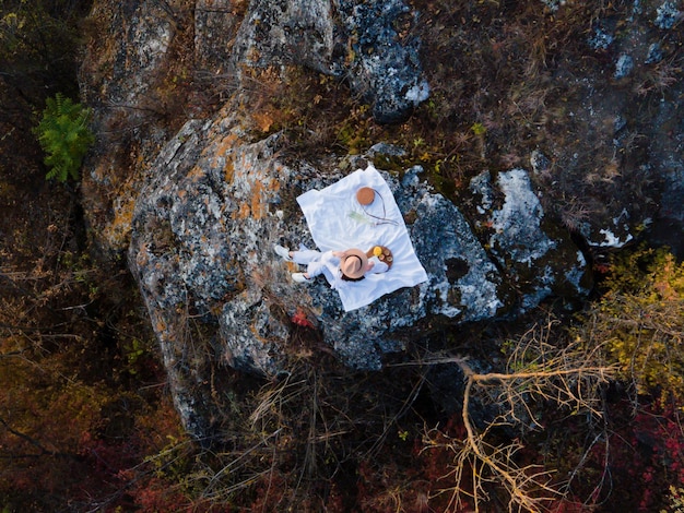 Aerial view of woman sitting at picnic on the rocky mountain from above