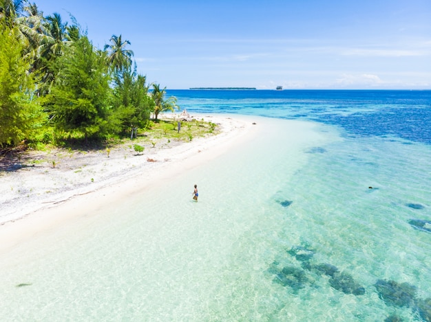 Aerial: Woman getting out of caribbean sea turquoise water tropical beach island