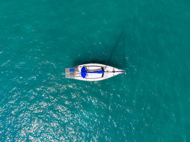 Aerial wonderful view of a enormous white and blue yacht sailing across the blue lagoona