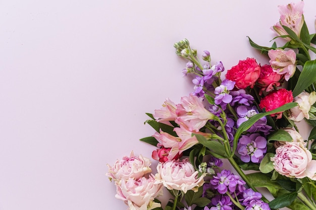 Aesthetic background with colourful red and pink rose flowers on pink background Beautiful floral composition