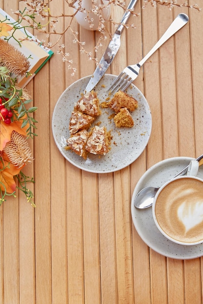 Aesthetic breakfast outside cutting doughnut among fall decorations Cappuccino in white ceramic cup on wooden table among flowers Lunch coffee time