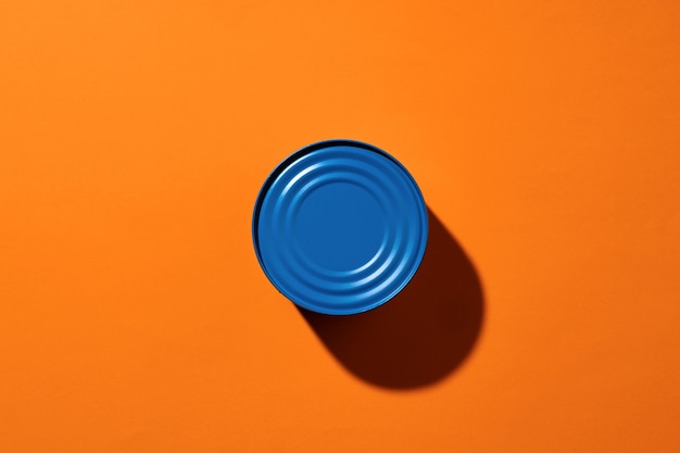 Aesthetic concept with blue painted tin can on orange surface