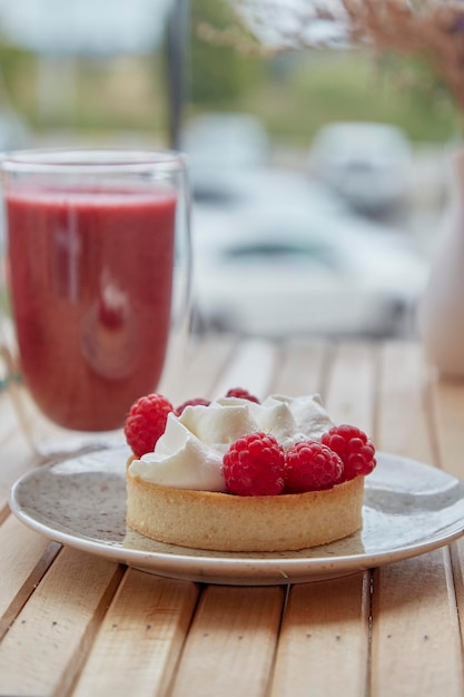 Aesthetic healthy autumn lunch pink strawberry smoothie and french tart on the wooden table