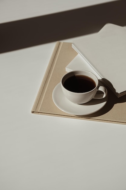 Aesthetic luxury bohemian minimalist concept Blank paper sheet note book cup of coffee album marble stone tray with sunlight shadows