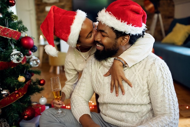 Affectionate black woman kissing her husband on New Year's day at home