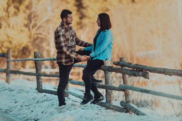 Affectionate couple holding hands and initiate eye contact against the background of the winter forest Selective focus