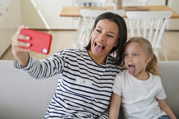 Photo affectionate mother and kid are taking selfie young european mum makes photo with little daughter