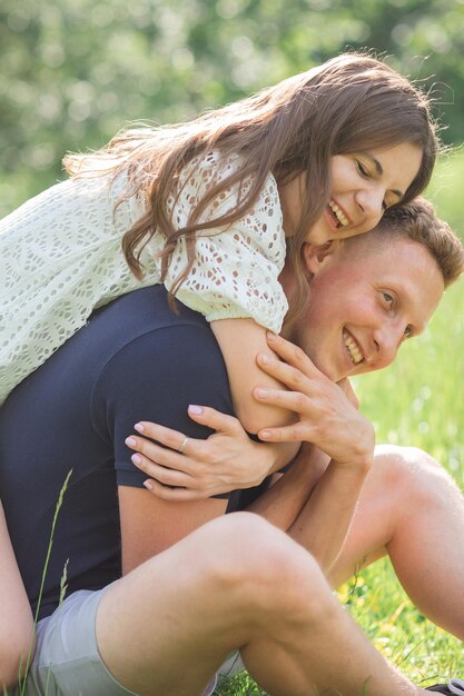 Affectionate young couple sitting on grass in park looking on each other young man and woman enjoyin