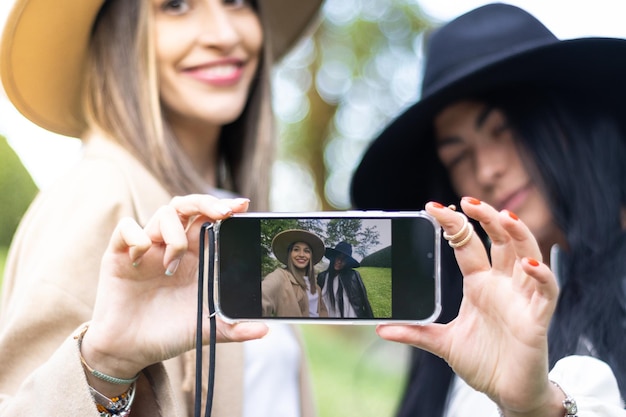 Affectionate young couple taking a selfportrait with a smartphone at the park teenage womans outdoors taking their picture with mobile phone