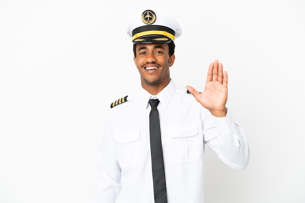 African American Airplane pilot over isolated white background saluting with hand with happy expression