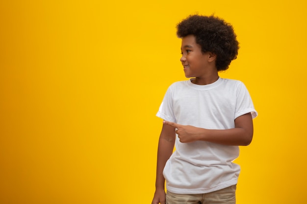 African American boy with black power hair on yellow . Smiling black kid with a black power hair. Black boy with a black power hair. African descent.