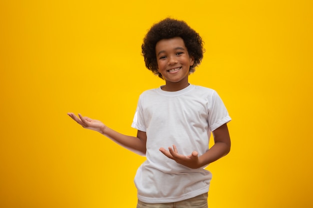 African American boy with black power hair on yellow . Smiling black kid with a black power hair. Black boy with a black power hair. African descent.