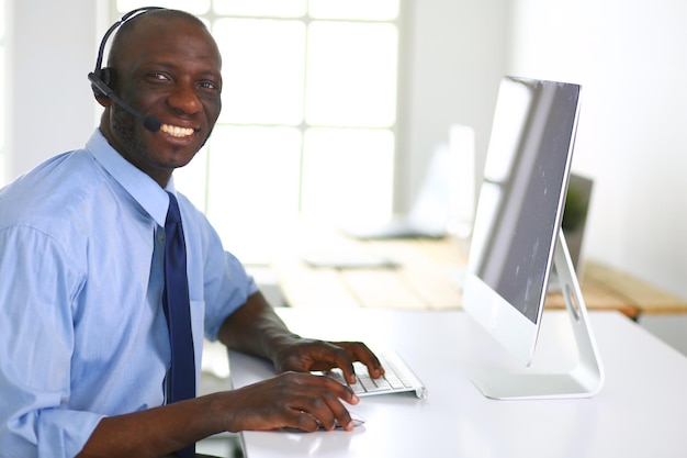 African american businessman on headset working on his laptop