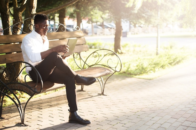 African-american businessman working at a laptop on a park bench