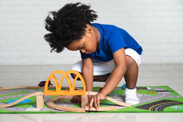 African American child playing with his car toys at home