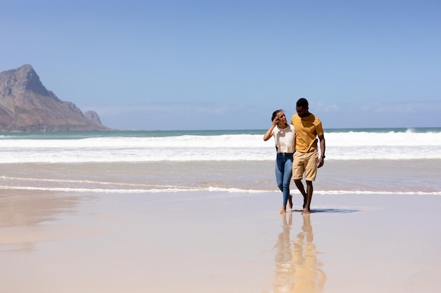 African american couple embracing walking on a beach by the sea. healthy lifestyle, leisure in nature.