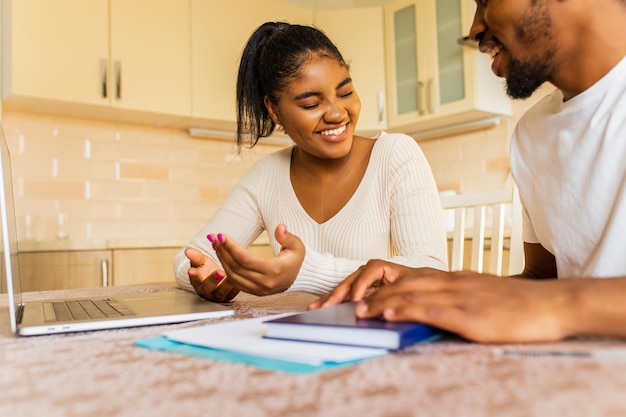 African american couple managing finances bank and using laptop at kitchen