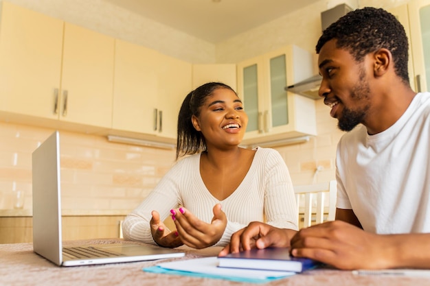 African american couple managing finances bank and using laptop at kitchen