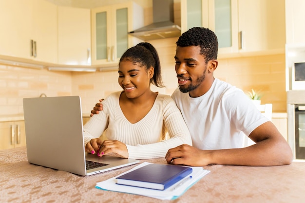 African american couple managing finances bank and using laptop at kitchen