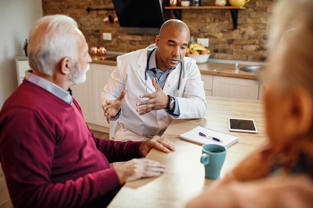 African American doctor communicating with mature couple during home visit