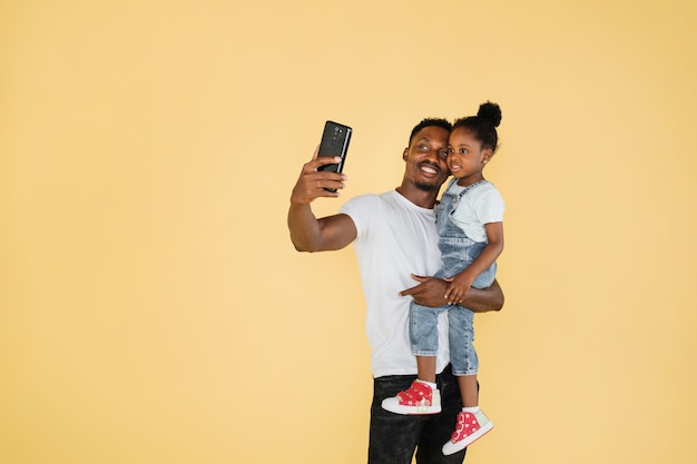 African American family dad and daughter having fun and using mobile phone video call