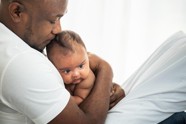 An African American father kissing head his 3 months old baby newborn son with happy and protection