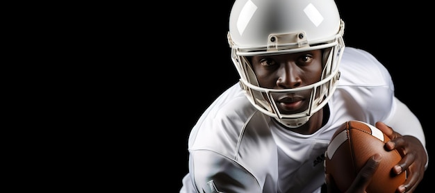 African American football player in white uniform and helmet holding football Closeup shot on black