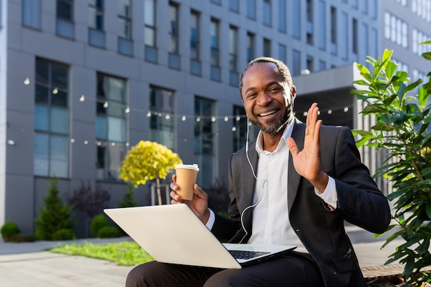 African american freelancer businessman sitting near office center with laptop and headphones he