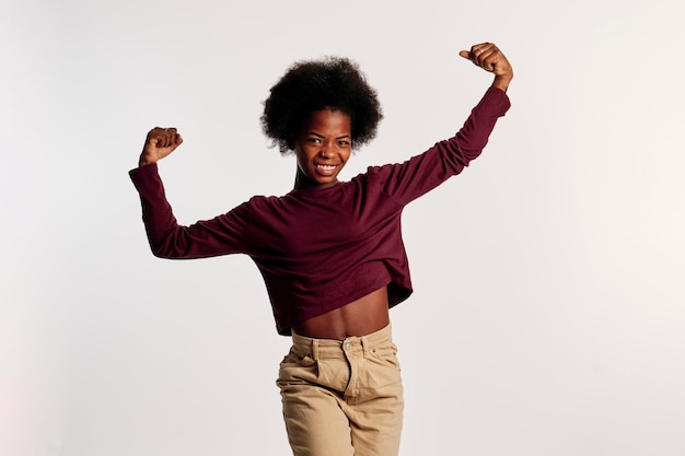 African american girl in brown sweater poses showing off her arms