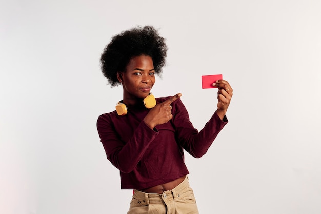 African American girl in brown sweater poses while showing her credit card.