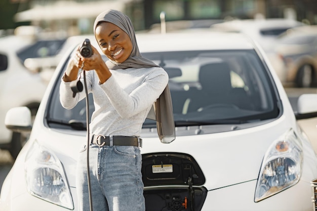 African American girl charging electro car at the electric gas station