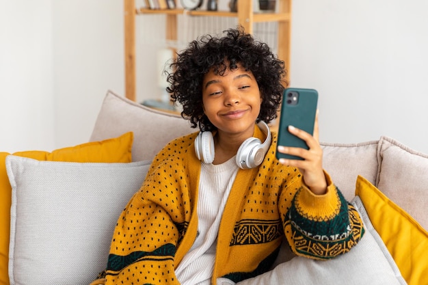 African american girl holding smartphone having video chat female blogger chatting with best friends