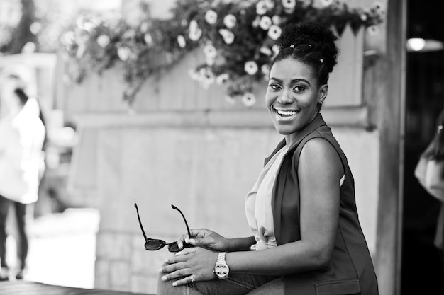 African american girl sitting outdoor with sunglasses at hands