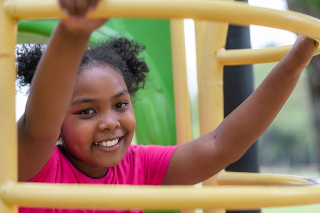 African American girl smiling look at camera while exercise at playground in the park