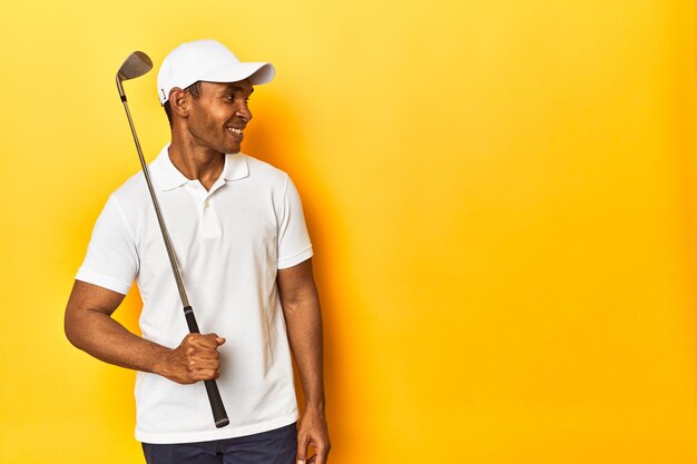 Photo african american golfer in action posed in a yellow background studio