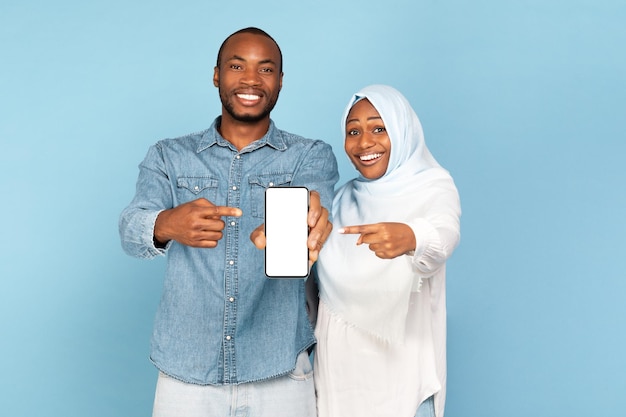 African American Islamic Couple Showing Phone Empty Screen Blue Background