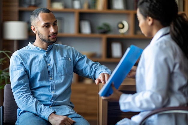 African american lady doctor showing patient treatment plan having conversation