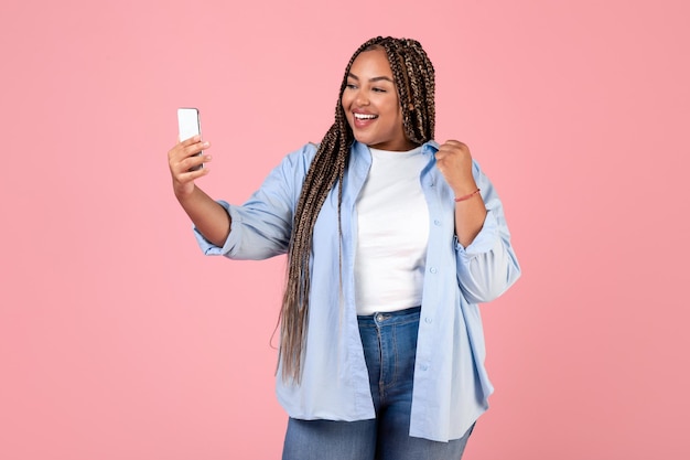 African American Lady Video Calling Holding Smartphone Over Pink Background