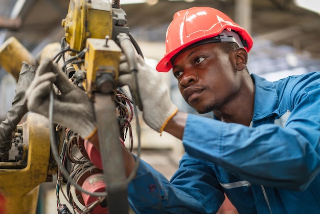 African American male engineer checking and repairing old robot arm in factory Industrial