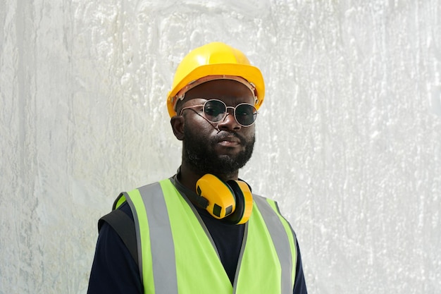 African american male engineer in safety helmet reflective vest and eyeglasses